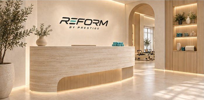 Curved travertine reception desk under the Reform by Prestige logo